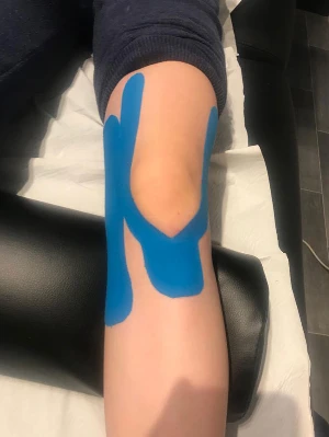 patient with blue Kinesiology tape around knee