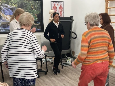 ladies standing up in falls prevention class being taken and lead by physiotherapist