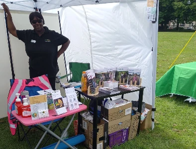 lotoya at an outside fair with two tables of products